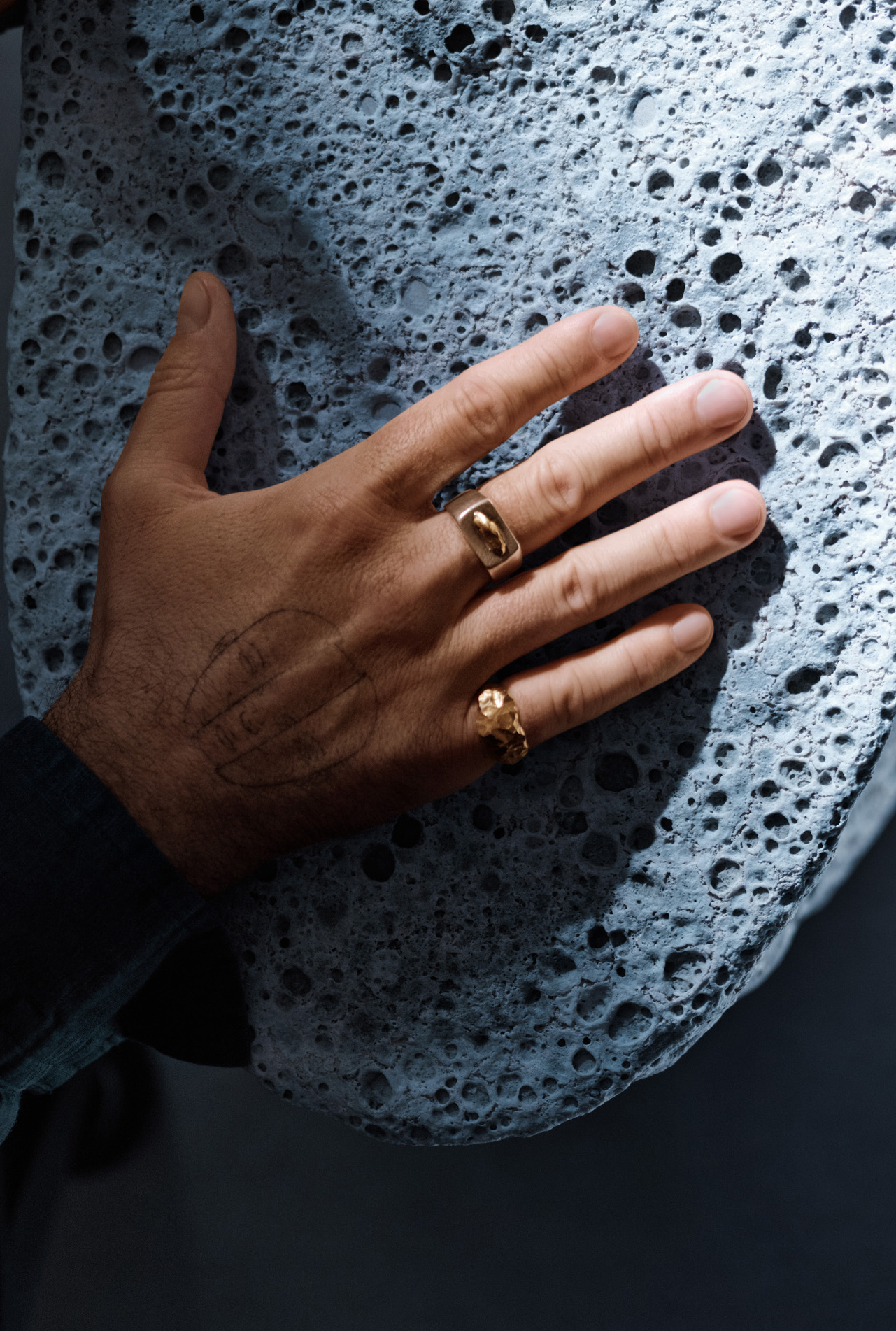 hand with rings touching pouros rock